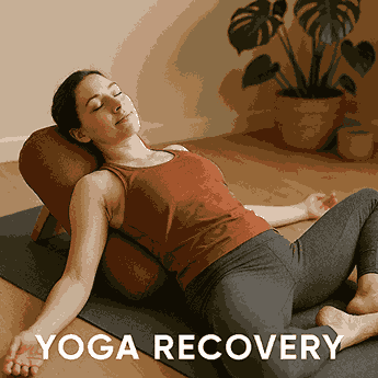 "Young woman in a restorative yoga pose using a bolster on a mat in a calm, sunlit room with wooden flooring and indoor plants."